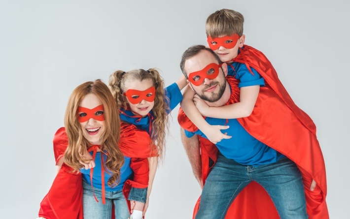 super parents piggybacking kids pretending to be superheroes isolated on grey